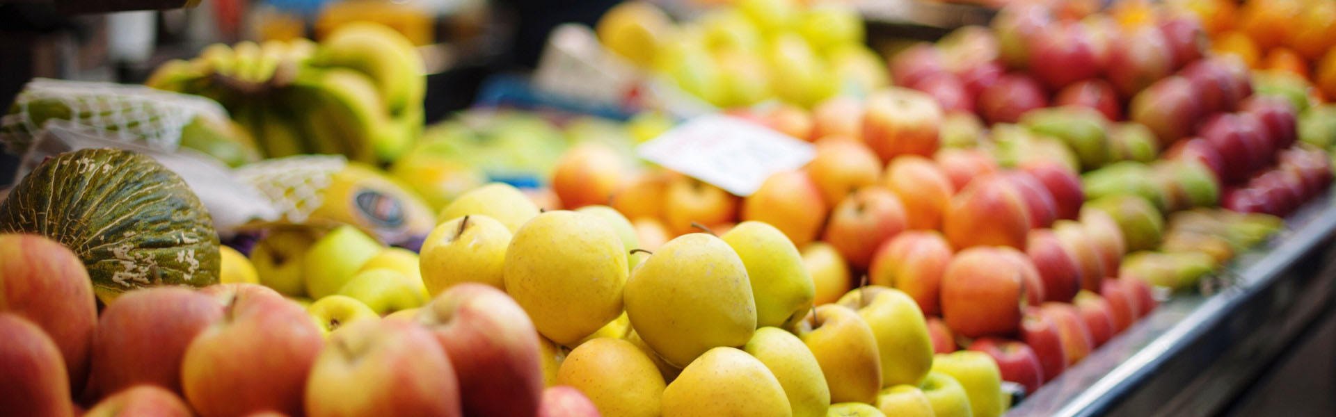 Bunter Obststand mit Äpfeln, Bananen und weiteren Früchten.